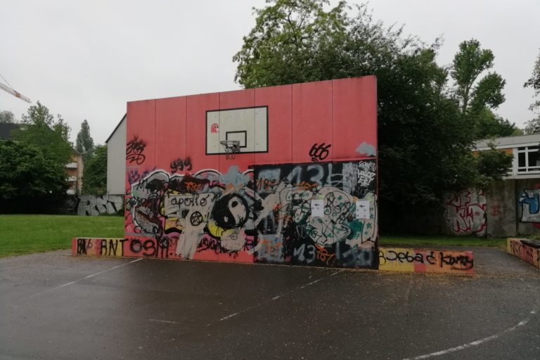 Basketballfeld mit vielen Graffitis an der Wand vom Korb